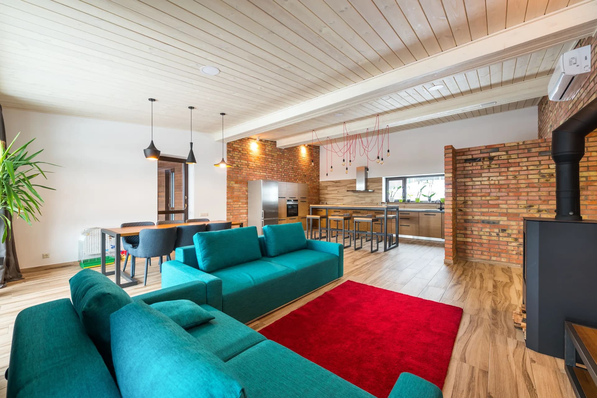 Exemple d'image BookNoFees : pièce à vivre ouverte avec un canapé turquoise, un mur en briques et une cuisine
