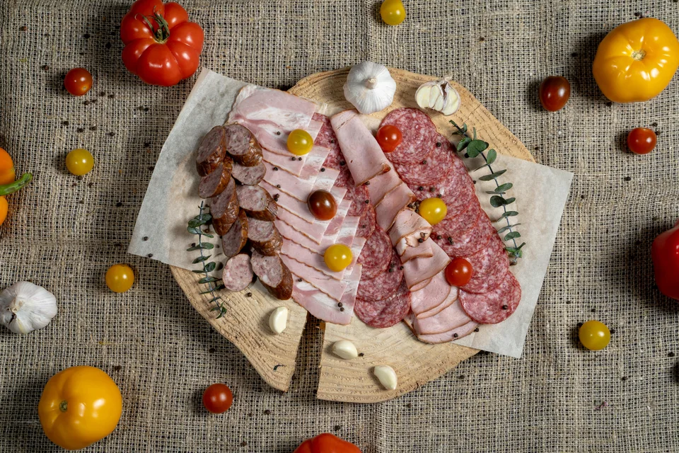 BookNoFees: Photo d’illustration : Tranches de charcuterie et de saucisses sur une planche en bois