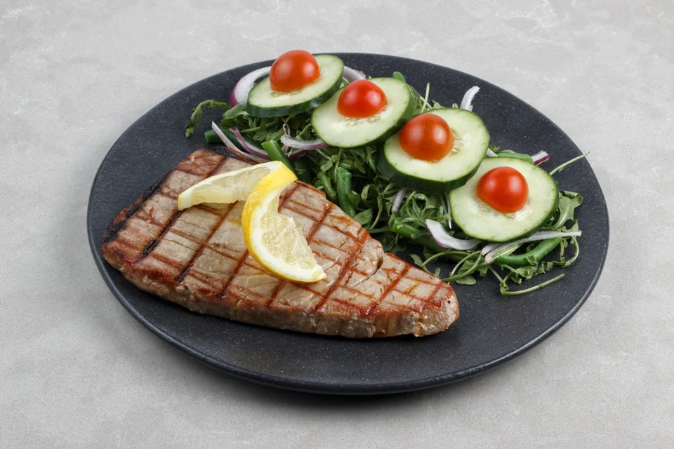 BookNoFees: Photo d’illustration : Steak de thon grillé accompagné d'une salade et d'un citron